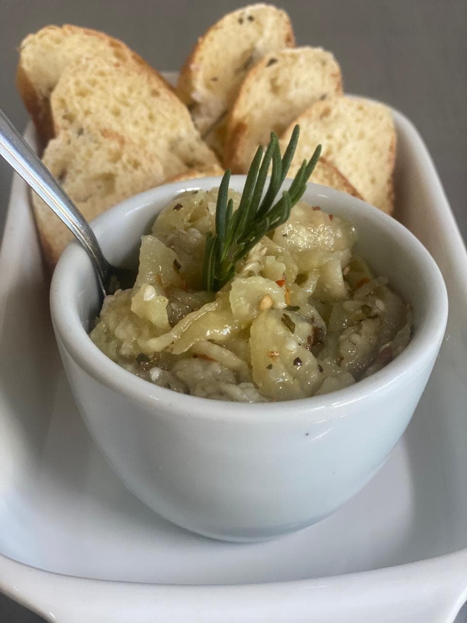 Antepasto servido em ramekin com torradas e alecrim