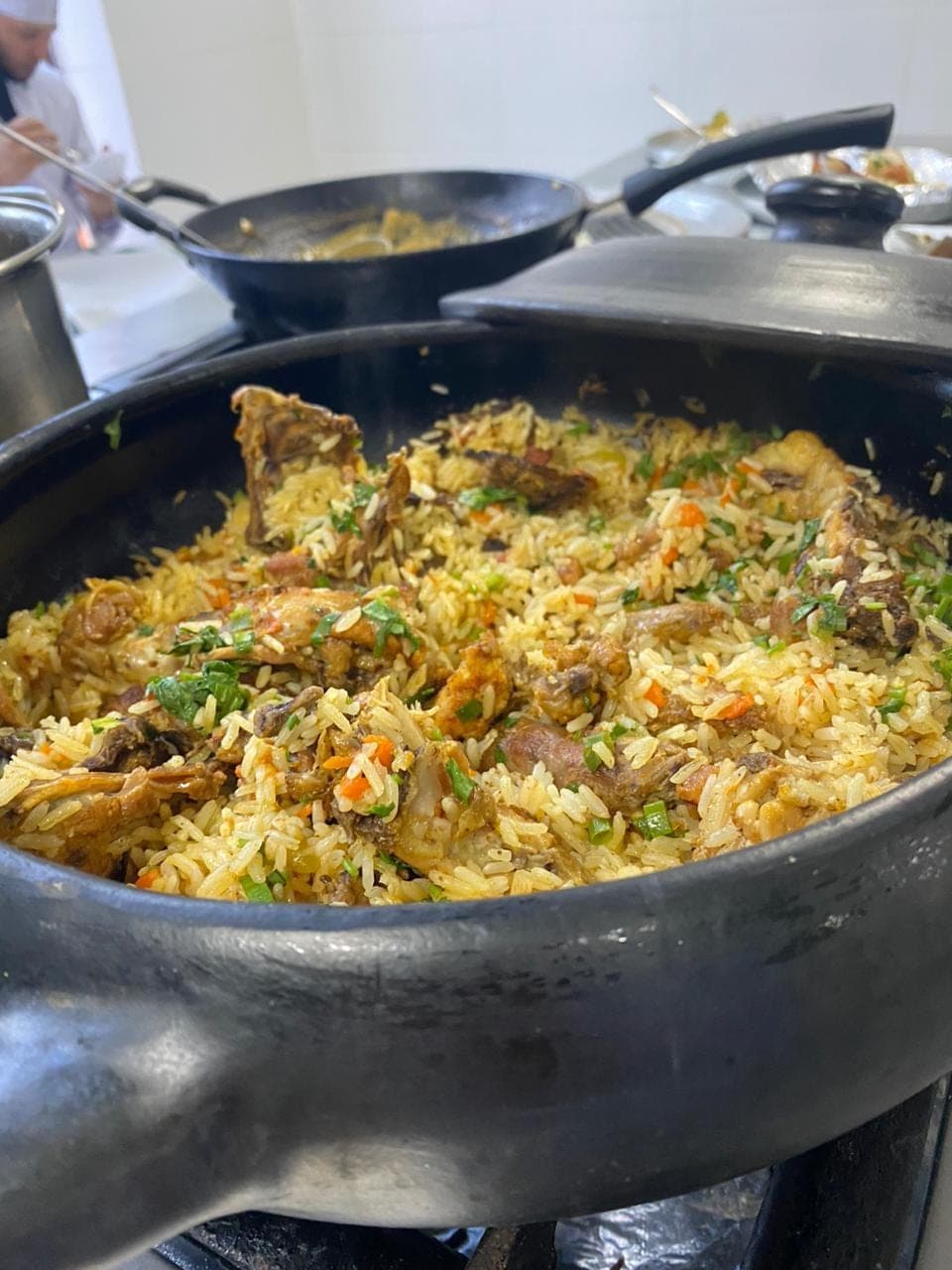 Panela larga de arroz com frango e ervas, em produção para um evento