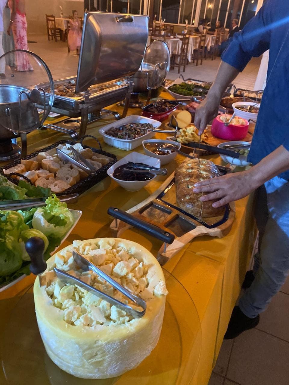 Queijo sendo porcionado no buffet enquanto os convidados se servem