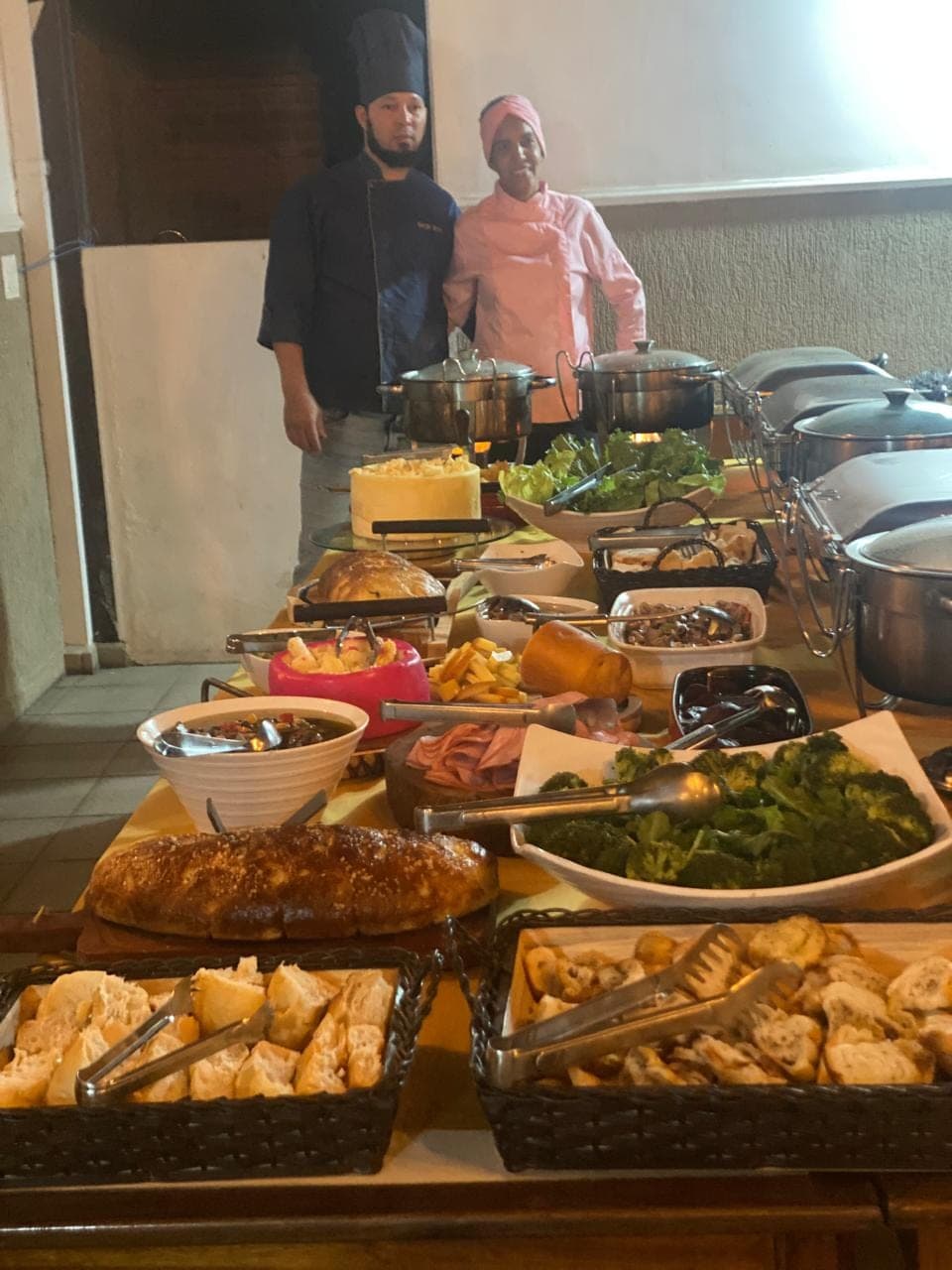 Equipe de cozinha uniformizada atrás da mesa de buffet montada para o evento