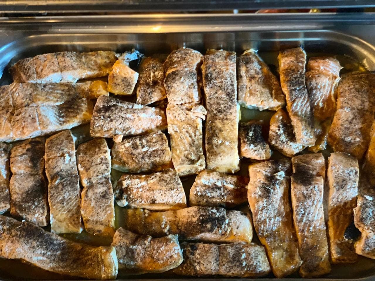 Filés de peixe grelhados alinhados no rechaud, prontos para o serviço
