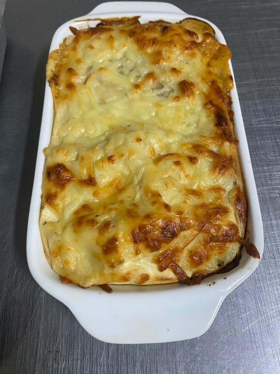 Lasanha gratinada em travessa branca, recém-saída do forno