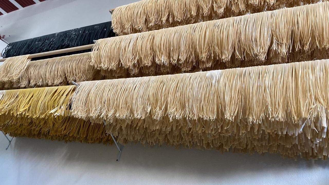 Fios de massa fresca pendurados no varal de secagem da cozinha de produção