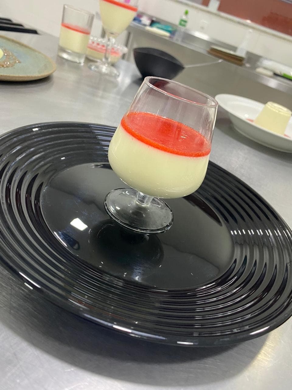 Panna cotta servida em taça com calda de frutas vermelhas