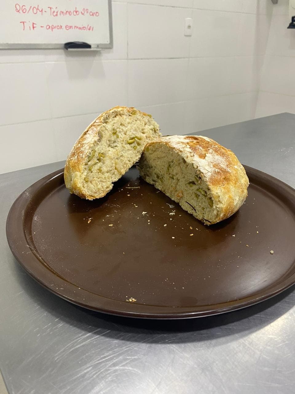 Pão artesanal partido ao meio sobre o prato, mostrando o miolo